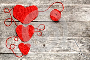 Three red knitted hearts on a gray wooden background, symbolizing love and family. Family relationship, bonds
