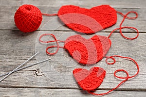 Three red knitted hearts on a gray wooden background, symbolizing love and family. Family relationship, bonds