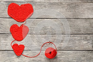 Three red knitted hearts on a gray wooden background, symbolizing love and family. Family relationship, bonds