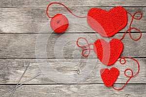 Three red knitted hearts on a gray wooden background, symbolizing love and family. Family relationship, bonds