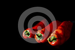 Three red pointed peppers lying in mood light