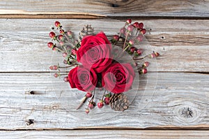 Three red roses in a cluster on rustic wood background