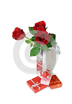 Three red roses in a silver gift bag and gift boxes