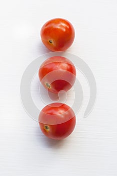 Three red tomatoes on a white .