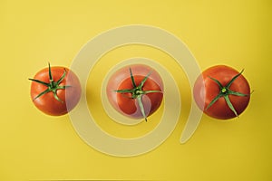 Three red tomatoes on yellow background. Complimentary color style.