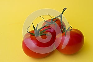Three red tomatoes on yellow background