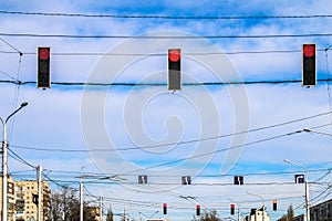 Three red traffic lights hang over the road against the blue sky. Prohibition signal.
