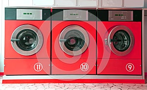 Three red washing machines in coin laundry