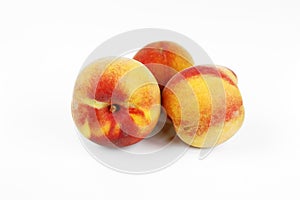 Three red and yellow coloured peaches on white ground