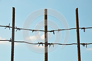 Three reinforcement with barbed wire against the blue sky.