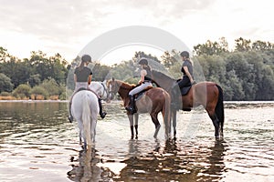 Three rider girls crossing the river riding their horses