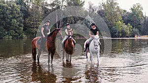 Three rider girls crossing the river riding their horses