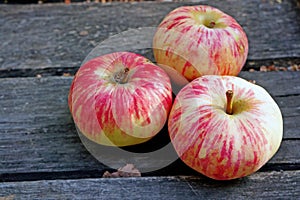 Three ripe apples on a rustic gray boards