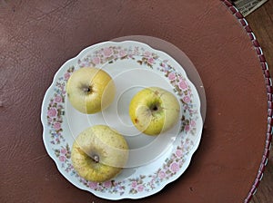 Three ripe apples on the saucer