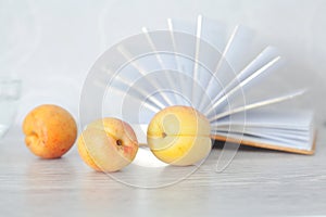 Three ripe apricots on background of open pages of book