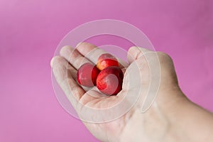 Three ripe fresh cherries in the palm of your hand. Close-up. Purple background. The concept of diet and healthy eating