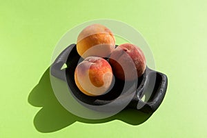 Three ripe juicy fluffy peach or nectarine on wooden serving plate. Bright sunlight & shadow, copy space