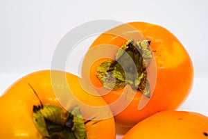 Poltava, Ukraine - 1 May, 2021: Three ripe orange persimmons Diospyros kaki on a white background photo