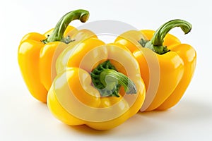 Three ripe yellow bell peppers arranged neatly on a plain white background