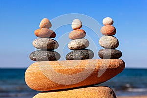 Three Rock zen pyramids of colorful pebbles on a beach on the background of the sea