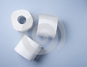 Three rolls of white toilet paper on a blue background. Pandemic, covid-19, essential goods, scarcity