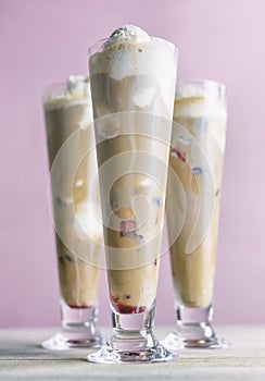 Three root beer floats made with vanilla ice cream and cherries. Pink background.