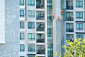 Three rope access workers painting the facade of a high modern building