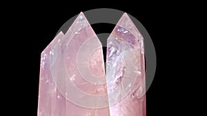 Three Rose quartz and Crystal on rotates on a black background