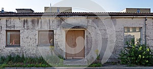 Three rotten curved windows in the yellow plastered  wall of a ruined old brick house