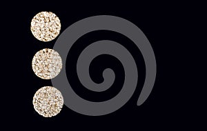 Three round rice crackers on a black vertical background close-up