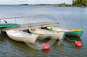 Three rowboats at wooden dock in sea bay
