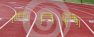 Three rows of yellow mini hurdles set up on a track for training