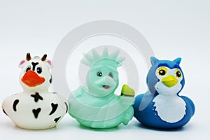 Three rubber ducks, a cow statue of liberty and penguin on an isolated white background