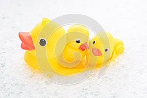 Three rubber ducks in foam water