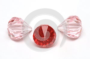 Three ruby red and light pink colored fake diamonds