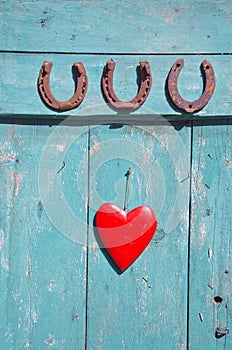 Three rusty horseshoe luck symbol and red heart on door