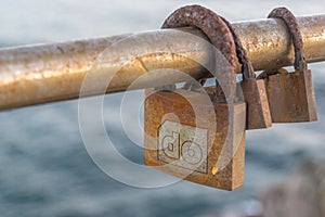 Three rusty Love padlocks over the sea