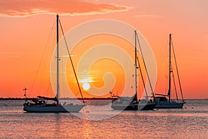 Three sailboats on sea at sunset