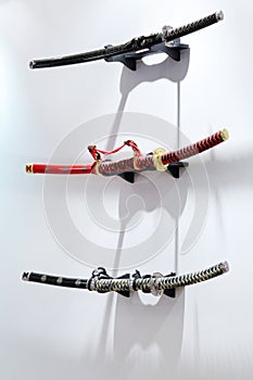 Three samurai swords hang on white wall