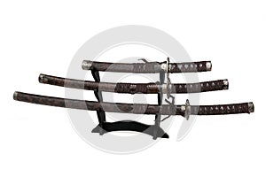 Three samurai swords on a stand on a white background