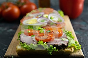 Three Sandwich with ham and tomatoes on wooden board