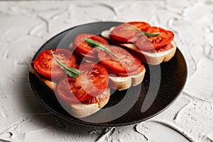 Three sandwiches with fresh and bright red tomatoes and smoked sausage, decorated with a leaf of green arugula