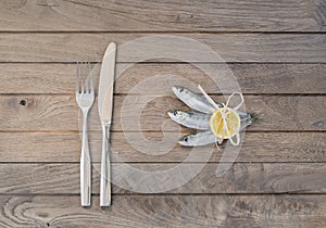 Three sardines and fork with knife