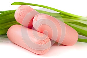 Three sausages with spring onions isolated on white background closeup