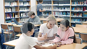 Three schoolchildren, who are engaged in lessons in the school library, make an synopsis of the necessary material from