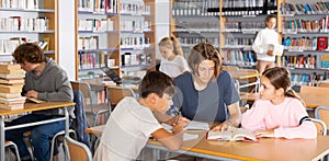 Three schoolchildren writes synopsis in an exercise book from the textbook