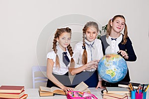 Three schoolgirls girls learn world geography lesson on the map