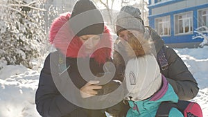 Three Schoolgirls in winter take a selfie on a smartphone on a Sunny winter day in the school yard.