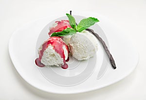 Three scoops of vanilla ice cream with strawberry syrup and mint on a white plate and a vanilla bean