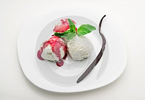 Three scoops of vanilla ice cream with strawberry syrup and mint on a white plate and a vanilla bean